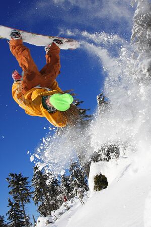 Snowboarder jumping against blue skyの写真素材