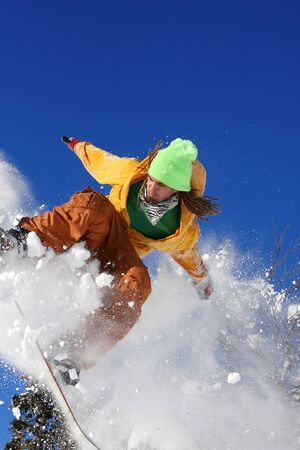 Snowboarder jumping against blue skyの写真素材