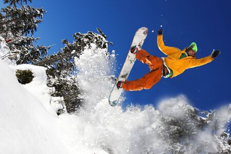 Snowboarder jumping against blue skyの写真素材