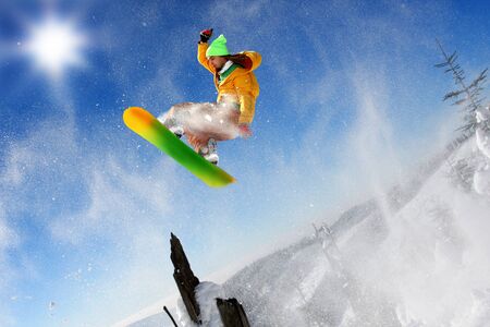 Snowboarder jumping against blue skyの写真素材