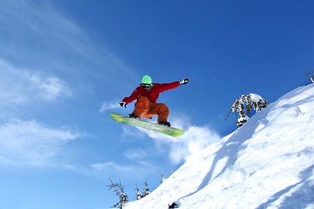 Snowboarder jumping against blue skyの写真素材