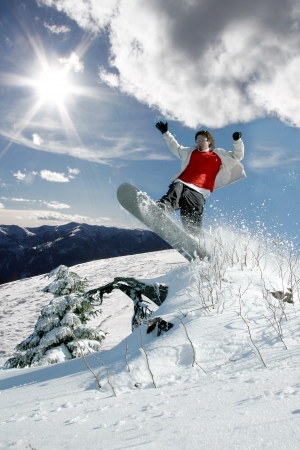 Snowboarder jumping against blue sky and sun raysの写真素材