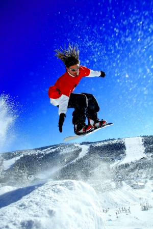 Snowboarders jumping against blue sky の写真素材