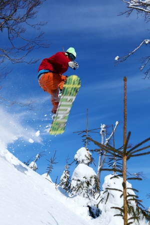 Snowboarders jumping against blue sky の写真素材