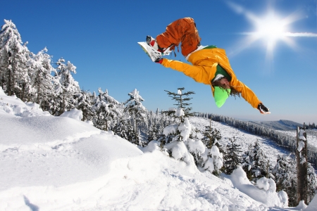 Snowboarder jumping against blue skyの写真素材