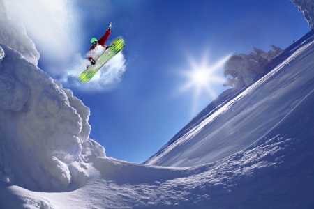 Snowboarder jumping against blue skyの写真素材