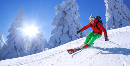 Skier skiing downhill in high mountains against blue skyの写真素材