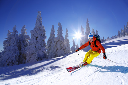 Skier skiing downhill in high mountains against sunsetの写真素材