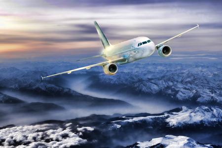 Airplane in the sky over winter Alps at amazing colorful sunset