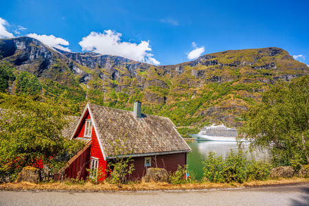 Red cottage against cruise ship in fjord, Flam, Norwayのeditorial素材