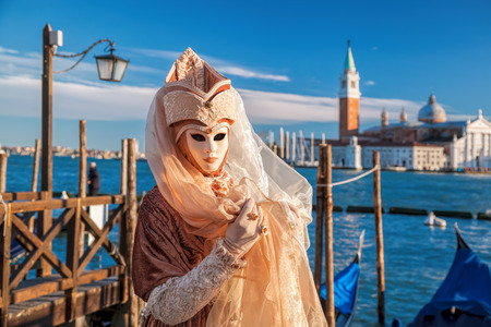 Famous carnival mask against gondolas in Venice, Italyの写真素材