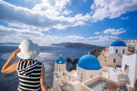 Woman with hat watching Oia village on santorini island in Greeceの写真素材