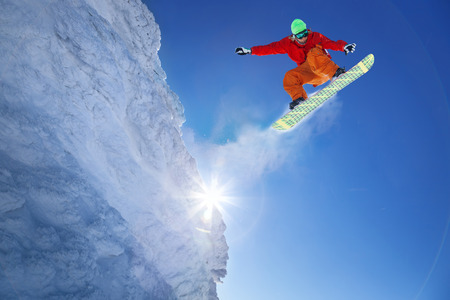 Snowboarder jumping against blue skyの写真素材