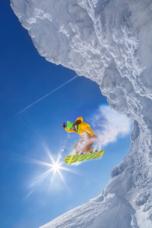 Snowboarder jumping against blue skyの写真素材
