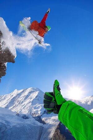 Snowboarder jumping against blue sky in high mountainsの写真素材