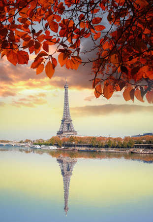 Eiffel Tower with autumn leaves against colorful sunset in Paris, Franceの写真素材