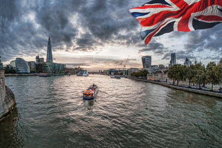 London with flag of England against boat on Thames river in England, UKの写真素材