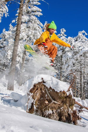 Snowboarder jumping against blue sky in high mountains
