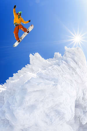 Snowboarder jumping against blue sky in high mountainsの写真素材