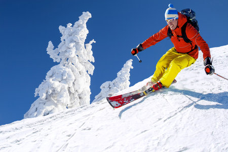 Skier skiing downhill in high mountains against against the fairytale winter forest.の写真素材