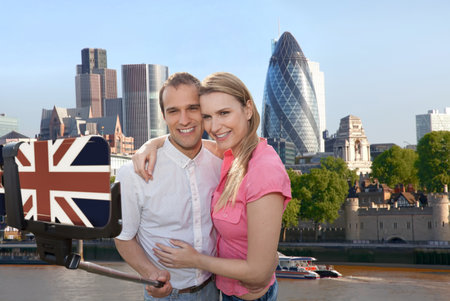 Couple in love taking a selfie portrait in front of modern skyscrapers on their way around London, England, UKの写真素材