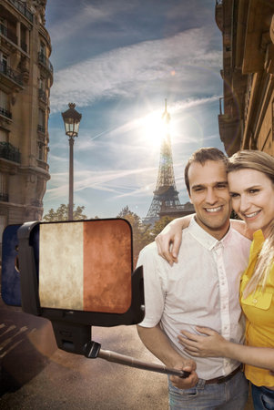 Happy couple of tourists taking selfie photo with cellphone covered a French flag in front of Eiffel Tower in Paris, Franceの写真素材