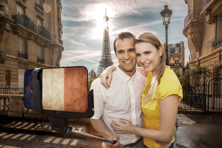 Happy couple of tourists taking selfie photo with cellphone covered a French flag in front of Eiffel Tower in Paris, Franceの写真素材