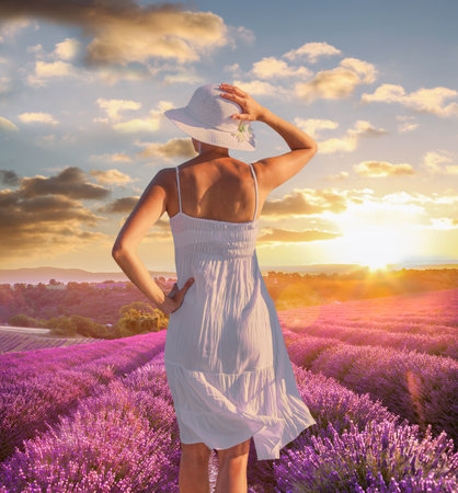 Woman holding hat in lavender fields in Provence, Franceの写真素材