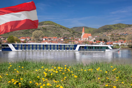 Weissenkirchen village with Austrian flag and boat on Danube river in Wachau, Austriaの写真素材