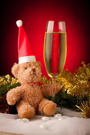 Plush bear with glass of sparkling wine on christmas decoration backgroundの写真素材
