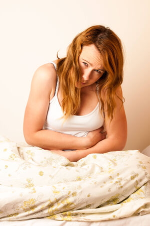 Woman feeling sick with stomachache in bed - havy Pain in stomachの写真素材