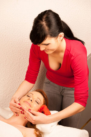Woman having face massage treatment in wellness centerの写真素材