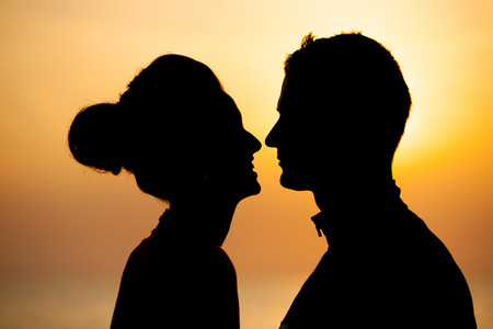 Silhouette of romantic couple on the beach at sunsetの写真素材