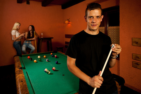 Man playing billiard in a bar at night