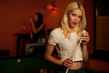 Beautiful young blonde playing billiard in a barの写真素材
