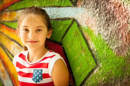 Young girl standing near graffiti wal on summer afternoon