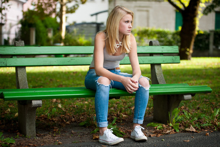 Beautiful blonde woamn rests on bench in parkの写真素材
