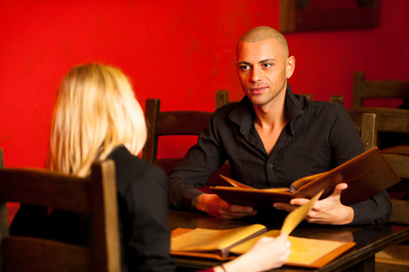 Young couple ordeting food in restaurant reading menu and decidingの写真素材