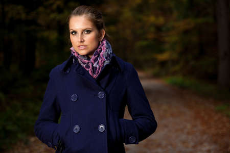 Pretty young woman on a walk in forest on late autumn day in fashoinable dressの写真素材