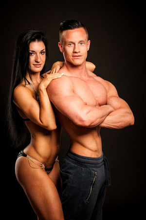 Fitness couple poses in studio - fit man and womanの写真素材