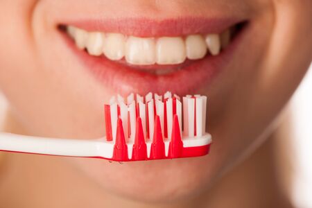 Woman holding toothbrush in front of teeth promoting mouth hygiene for healthy teeth.の写真素材
