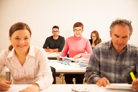 Group of people of different age sitting in classroom and attending a school for adults. Lifelong learning.の写真素材