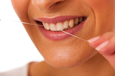 Woman cleaning teeth with dental floss for perfect hygiene and healthy teeth.