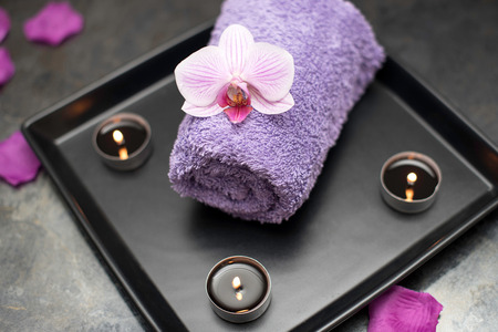 Beauty salon decoration in massage room, candles, towel and orchid.