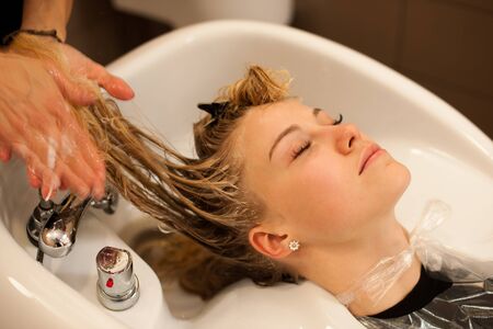Hair stylist at work - hairdresser washing hair to the customer before doing hairstyleの写真素材