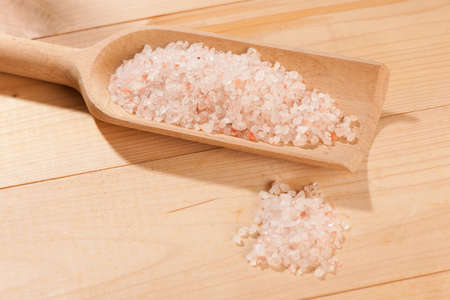 wooden spoon full of stone salt on a tableの写真素材