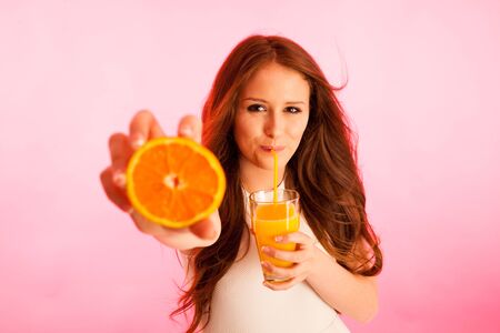 Woman drinking orange juice smiling showing oranges. Young beautiful  Caucasian model.の写真素材