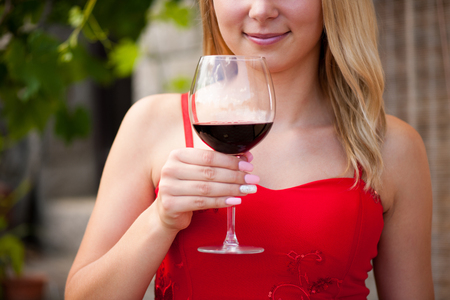 Beautiful woman drinks red wine outdoor on a hot summer afternoonの写真素材