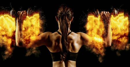 Atractive fit woman works out with dumbbells as a fitness conceptual over dark background.の写真素材