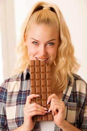 Beautiful blonde woman eats a big chocolateの写真素材